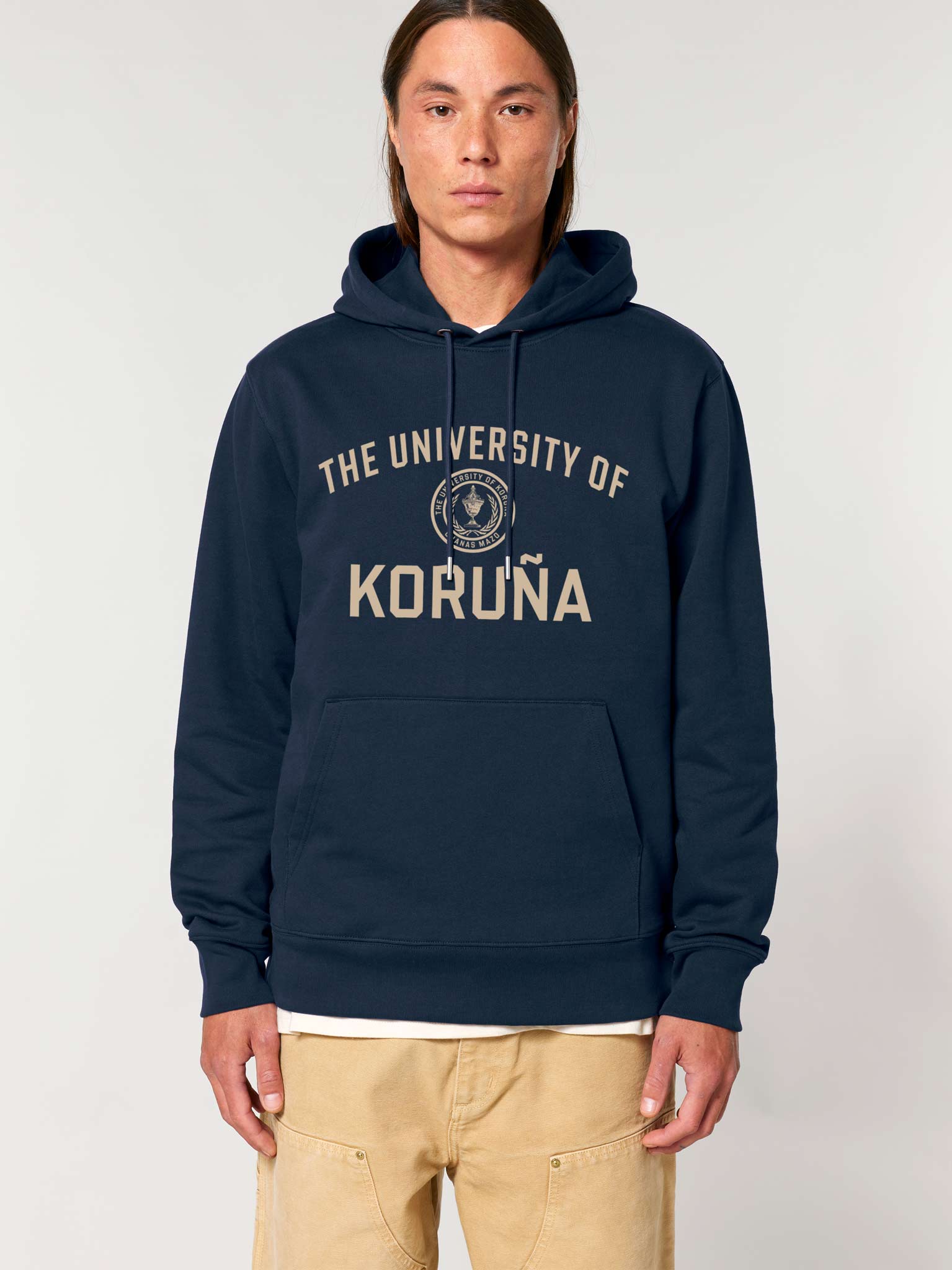 Hombre posando con sudadera azul marino y diseño impreso de "The University of Koruña" en color arena.